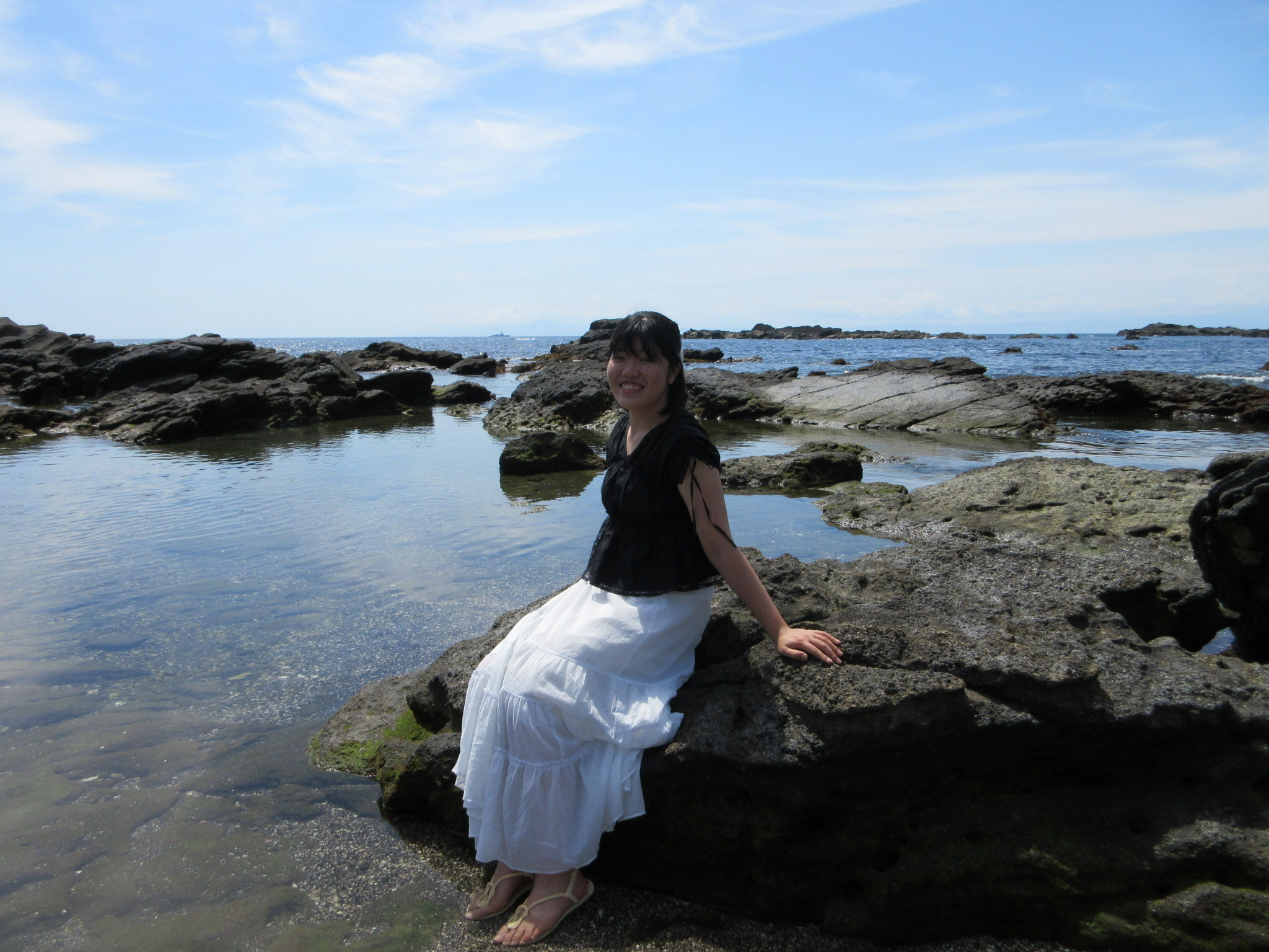 Me at a beach, sitting on a rock